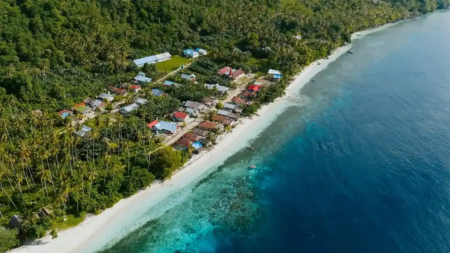 Aerial view of a seaside village along a white sand beach and reef